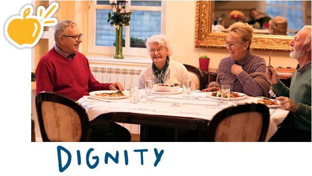 Elderly residents eating dinner and having a laugh