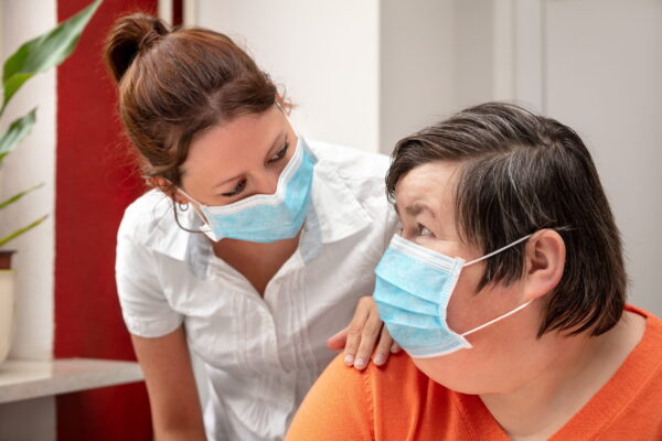 Senior citizen in a mask speaking to a healthcare professional