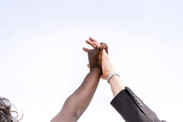 Two hands joined together in triumph against a white-gray sky