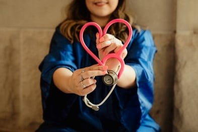 Female healthcare provider holding a stethoscope bent into the shape of a heart