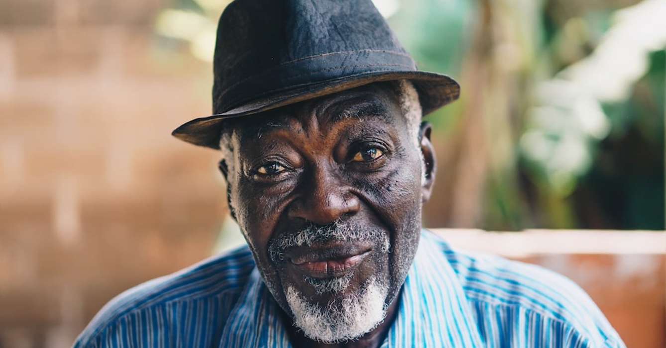 Older man with black hat and blue shirt smiling