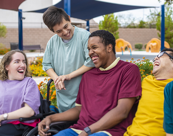 Group of teens sitting in a park laughing.