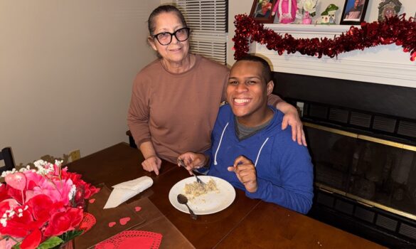 Staff and Individuals VA 1.12.26-065 Woman serving a plate of food to a man sitting at a table.