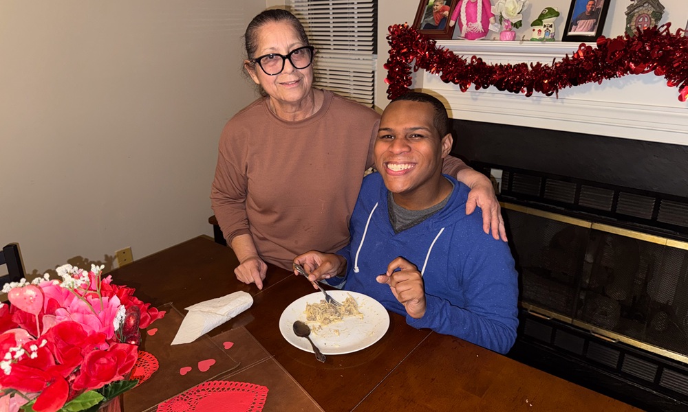 Woman serving a plate of food to a man sitting at a table.