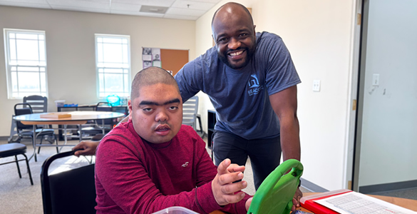 va-behavioral-5 Man assisting a student at a day program.