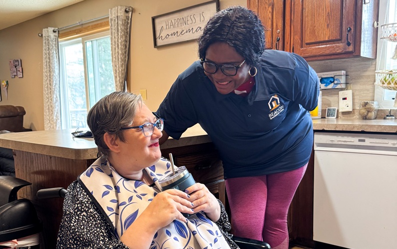 Staff and Individuals MN-10 Caretaker helping a handicapped woman in the kitchen.