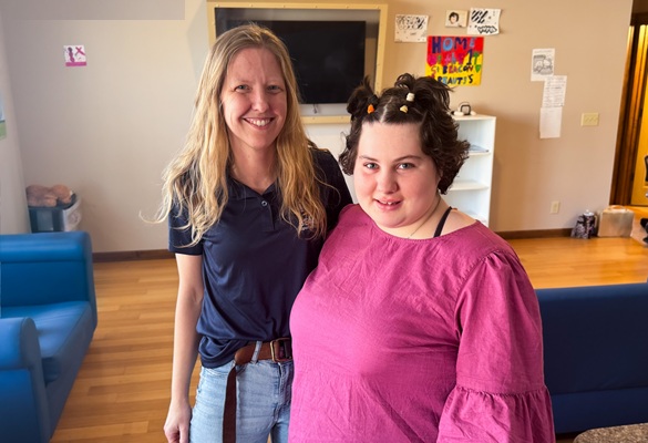 about-us-care-team-1 Two women standing side by side in a living room.